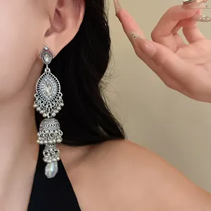 Close-up of vintage palace-style silver earrings with rhinestones and a faux pearl on ear.