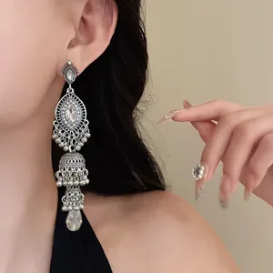 Detailed view of vintage silver jhumka earrings with crystal accents on a model's ear
