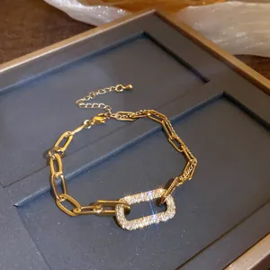 Macro view of gold-tone geometric link bracelet with shimmering pavé rectangular charm.