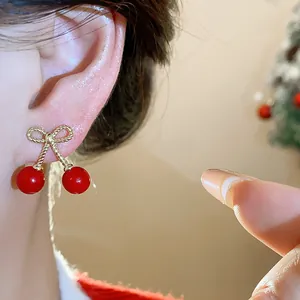 Close-up of red bow cherry earrings showing delicate metal textures and vibrant color