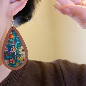 Detailed view of bohemian teardrop wood earrings with colorful floral stained glass print