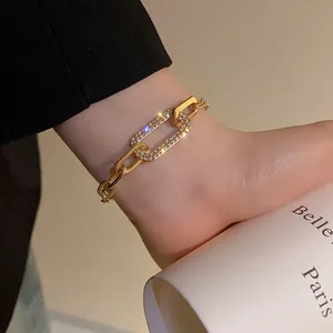 Close-up of a gold geometric chain bracelet with sparkling pavé-set rhinestones.