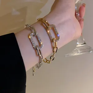 Close-up of elegant gold and silver chain bracelets with sparkling crystal links.
