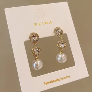 Elegant gold-plated drop earrings featuring sparkling rhinestones and lustrous round white pearls