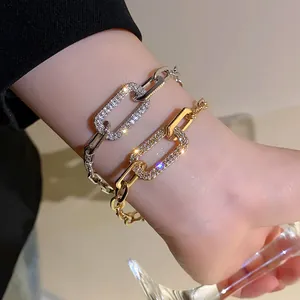 Close-up of gold and silver rectangular pave rhinestone link chain bracelets on wrist