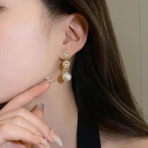 Elegant gold plated pearl drop earrings with crystal accents shown on model's ear