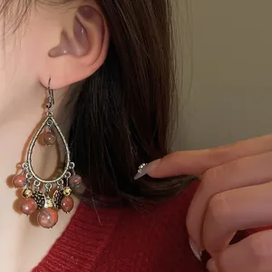 Vintage style tear-drop tassel earrings with marbled beads and gold charms on model