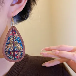 Close-up of bohemian wooden teardrop earring with vintage stained glass floral print.