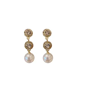 Elegant gold-tone drop earrings featuring circular rhinestone studs and round white pearls