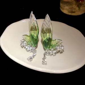 Close-up showing the detail of green fairy wing ear clips with sparkling crystal flowers.