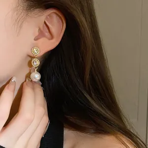 Close-up of elegant French style gold earrings with rhinestones and a white pearl