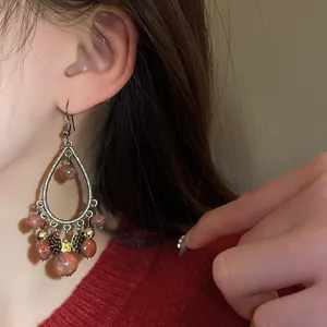 Close-up detail of vintage water-drop tassel earrings featuring reddish stone beads.
