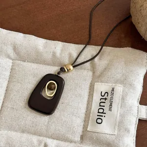 Macro view of minimalist resin pendant necklace featuring tiger eye stone and gold ring