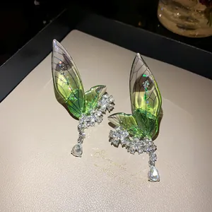 Close-up of elegant emerald green fairy wing ear cuffs with crystal flower details
