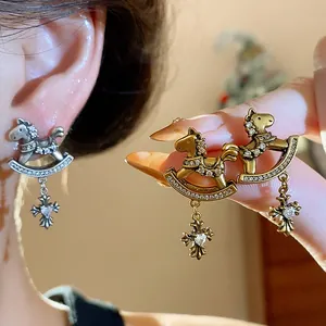 Detailed view of vintage rocking horse earrings with zircon cross pendants