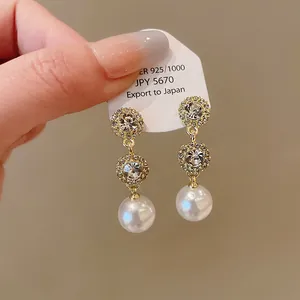 Close-up of French luxury earrings with sparkling crystals and elegant round pearls.