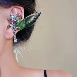 Detailed macro view of a green fairy wing ear cuff with rhinestones and floral patterns