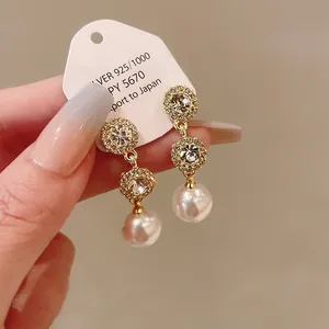 Detail view of elegant silver earrings featuring tiered rhinestones and pearl drops