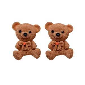 Sweet brown flocked bear stud earrings featuring red bow details on white background
