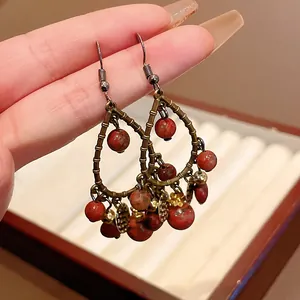 Close-up of vintage teardrop tassel earrings with reddish beads and bronze metal finish