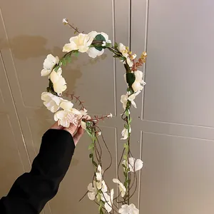 Detailed view of a cream floral wreath headband with delicate vine and tassel accents.