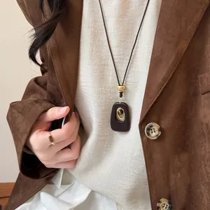 Close-up of a resin elliptical pendant necklace featuring a tiger eye stone on a model