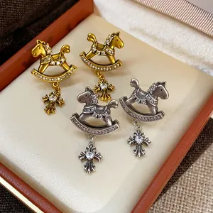 Vintage rocking horse stud earrings with zircon-encrusted heart cross charms in jewelry box