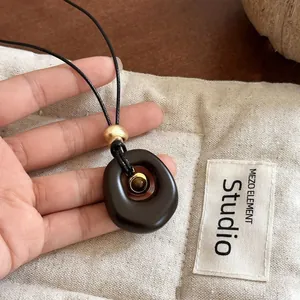 Detailed view of handmade oval resin pendant necklace featuring a central tiger eye stone bead