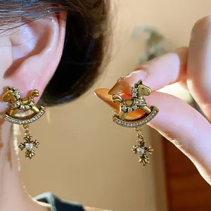 Detail view of vintage gold rocking horse earrings with cross charm and zircons