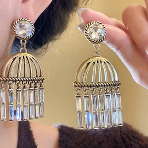 Detailed view of vintage-style gold earrings with zircons and hollow bar tassels.