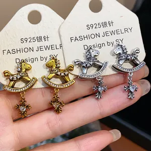 Detailed view of vintage rocking horse earrings with zircon cross pendants on cards