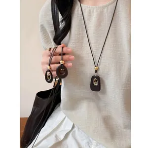 Detailed macro shot of tiger eye stone and resin pendant necklaces on a linen shirt