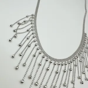 Gros plan d'un collier argenté avec des franges et des glands de perles fins