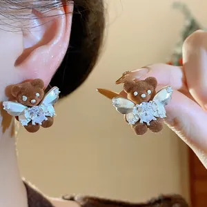 Close-up of sweet brown flocked bear earrings with silver wings and sparkling zircon stone