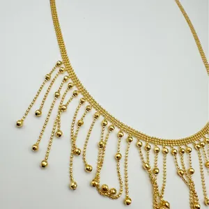 Gros plan d'un collier à franges géométriques dorées avec détails de chaîne à billes.