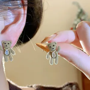 Detailed close-up of a brown flocked teddy bear stud earring with sparkling zircon inlay
