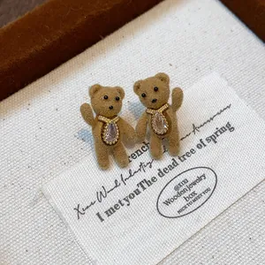 Close-up of brown flocked teddy bear earrings with sparkling crystal pendants in gold finish