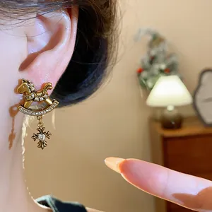 Detailed close-up of vintage golden rocking horse earring with zircon-encrusted cross