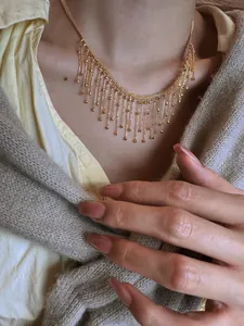Gros plan d'un élégant collier à pompons dorés avec franges géométriques