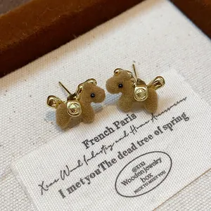 Close-up of brown flocked teddy bear stud earrings with gold accents on jewelry box