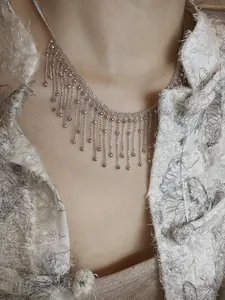 Collier ras-du-cou élégant à franges géométriques argentées sur mannequin avec veste chic.