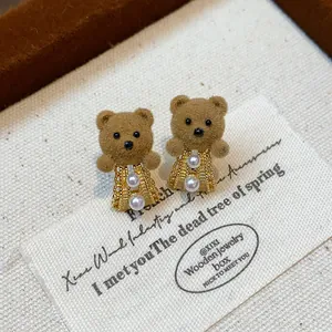 Close-up detail of cute flocked teddy bear earrings with pearls and 18K gold plating.