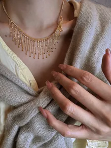 Gros plan d'un collier à franges doré élégant avec des glands en perles sur le cou