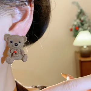 Detailed view of a sweet brown flocked teddy bear ear stud worn on a woman's ear