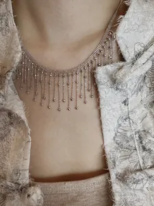 Gros plan d'un collier à franges géométriques argentées montrant des détails complexes