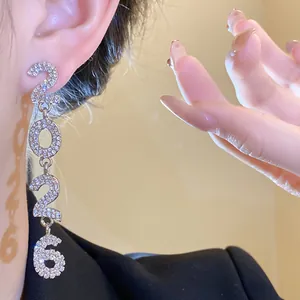 Close-up of 2026 silver tassel earrings with sparkling rhinestones on model's ear.