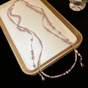 Detail of a pink double-layer pearl necklace featuring elegant teardrop crystal pendants.