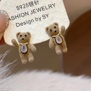 Macro view of brown flocking teddy bear stud earrings with teardrop crystal centerpiece