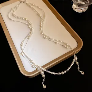 Elegant double-layered pearl necklace featuring shimmering rhinestone teardrop pendants details.