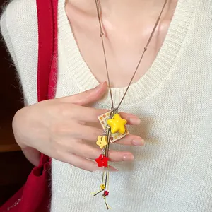Detail shot of a vibrant dopamine star pendant necklace worn on a white knit sweater.